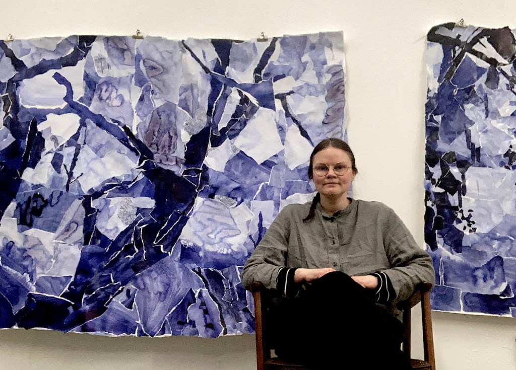 Swedish artist,  Susan Whitlow, sitting in her studio in front of her abstract paintings. 